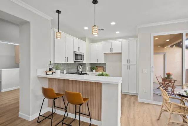 a kitchen with stainless steel appliances kitchen island granite countertop a dining table chairs and white cabinets