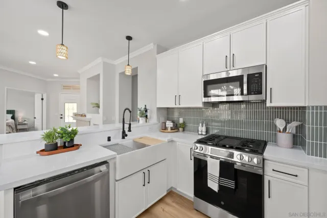a kitchen with stainless steel appliances white cabinets sink and stove