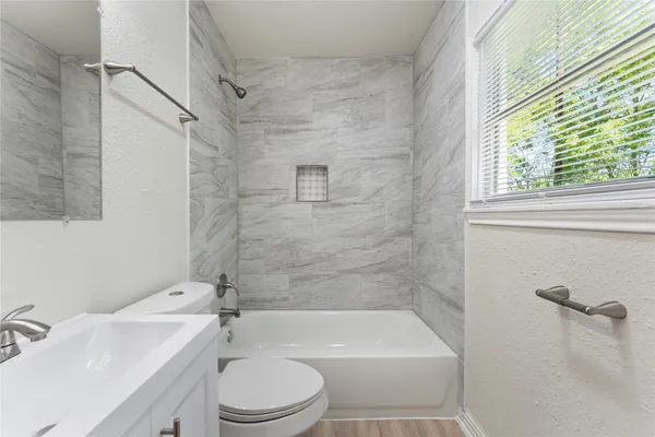 a bathroom with a bathtub shower sink vanity and toilet