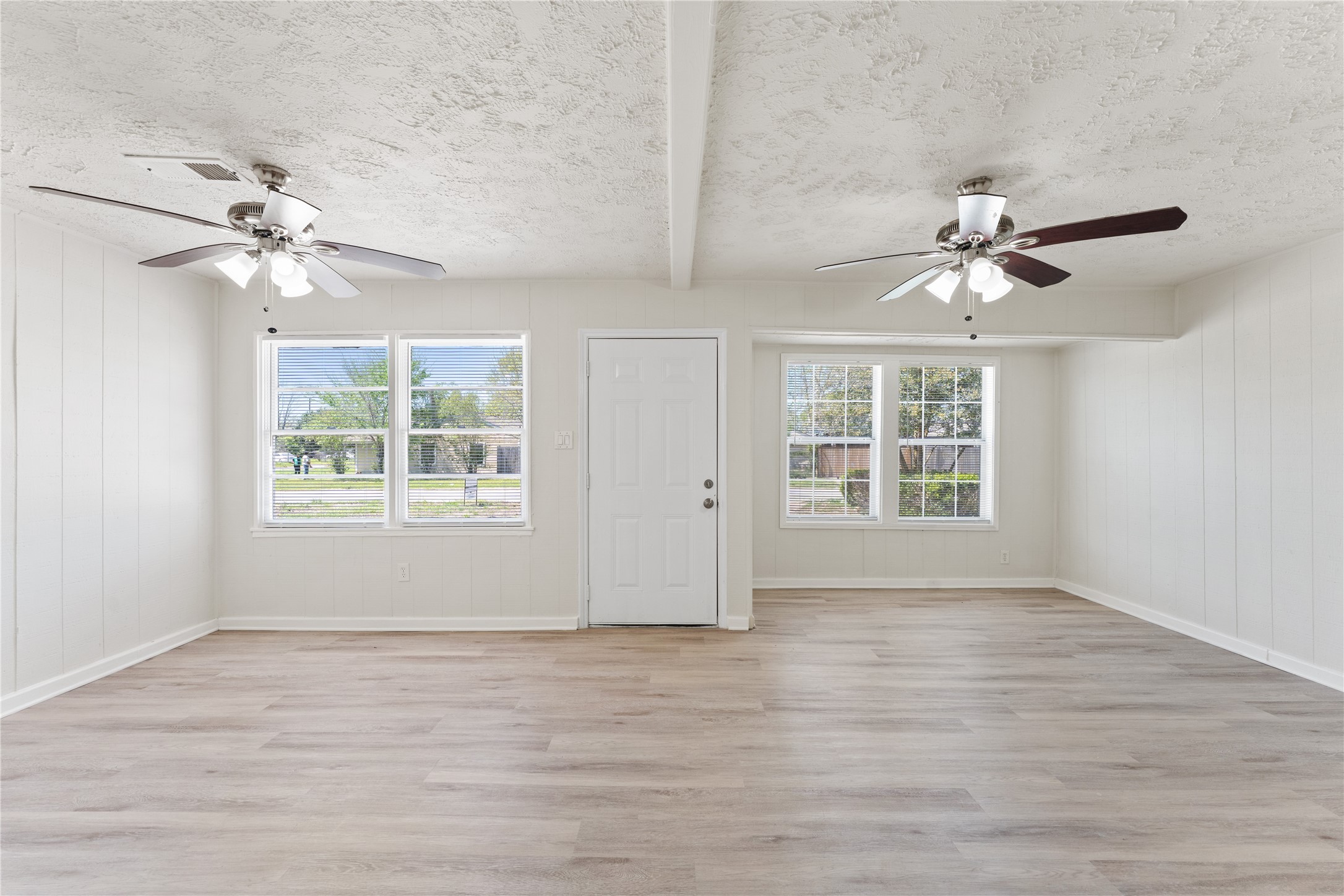 7725 St Lo Road Houston, TX 77033 - Photo 6 of 26 an empty room with wooden floor chandelier fan and windows