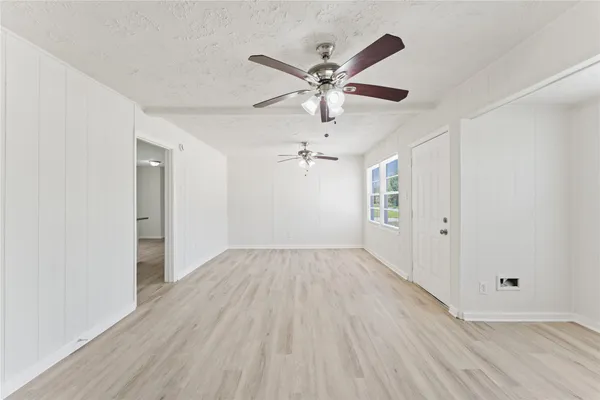 an empty room with wooden floor fan and windows