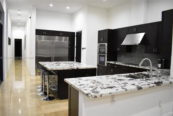 a kitchen with kitchen island granite countertop a sink and a stove