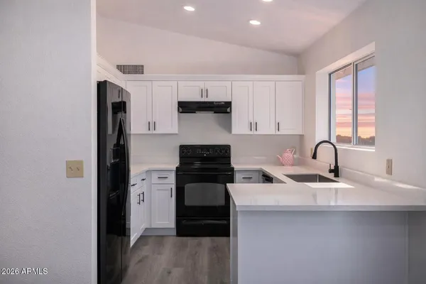 a kitchen with stainless steel appliances granite countertop a stove a sink and a refrigerator with wooden floors