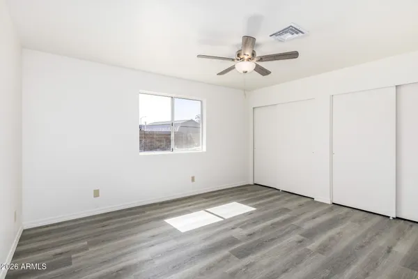 an empty room with wooden floor fan and windows