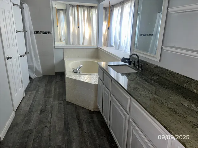 a bathroom with a granite countertop sink a toilet a mirror and window