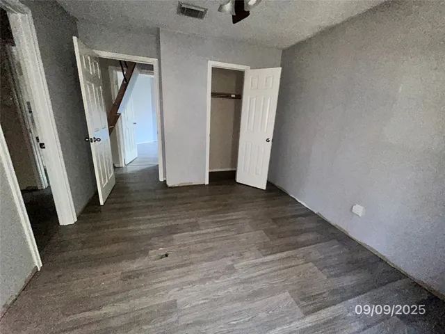 an empty room with wooden floor and stairs