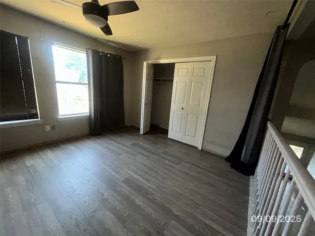 an empty room with wooden floor and windows