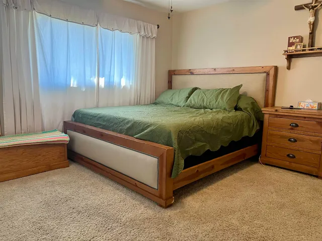 a bed sitting in a spacious bedroom next to a window and a mirror