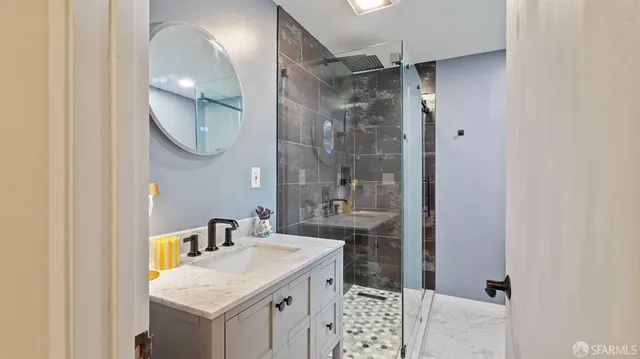 a bathroom with a granite countertop sink a mirror a vanity and a shower