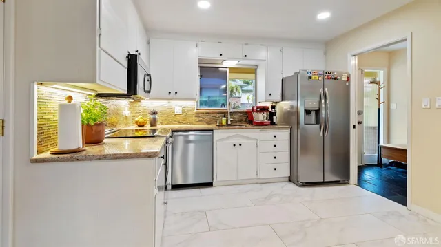 a kitchen with white cabinets and refrigerator