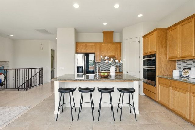 a kitchen with stainless steel appliances kitchen island granite countertop a table chairs in it and wooden floors