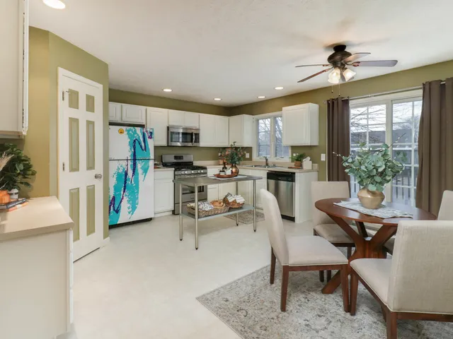 a living room with stainless steel appliances furniture a dining table and a chandelier