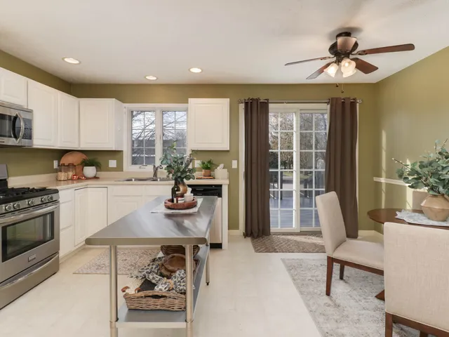 a kitchen with stainless steel appliances granite countertop a stove a refrigerator a sink a dining table and chairs with wooden floor