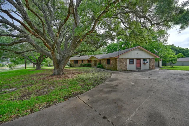 a front view of house with a garden and trees