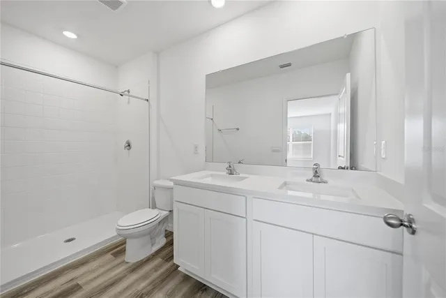 a bathroom with a double vanity sink toilet and shower