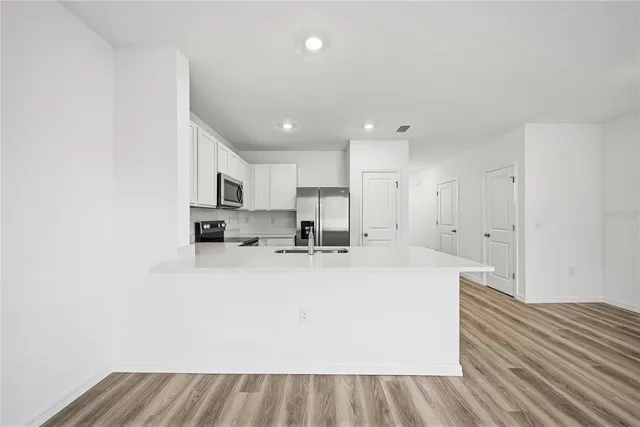 a large white kitchen with wooden floors and white cabinets