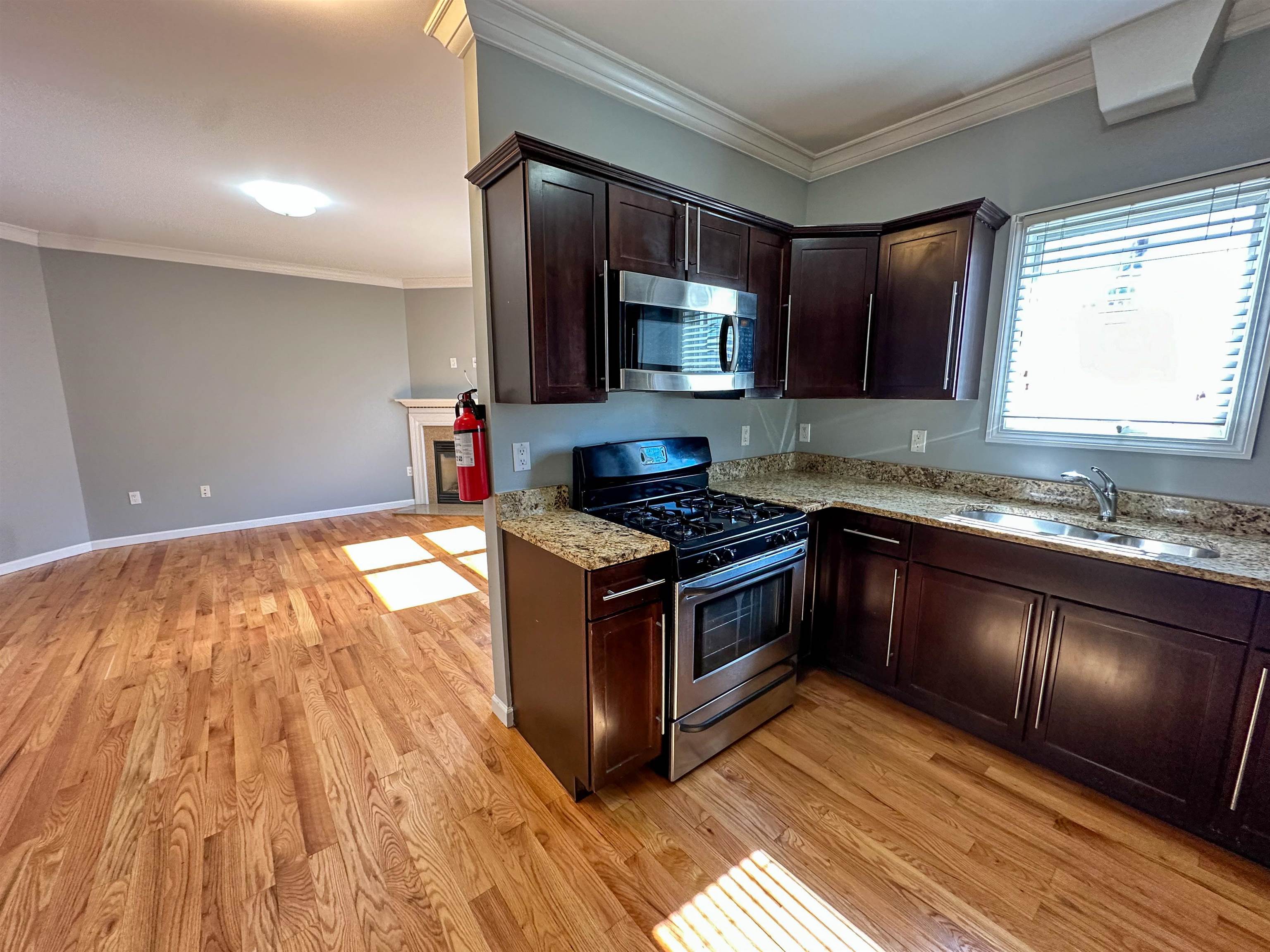 a kitchen with stainless steel appliances granite countertop a stove a sink and a microwave