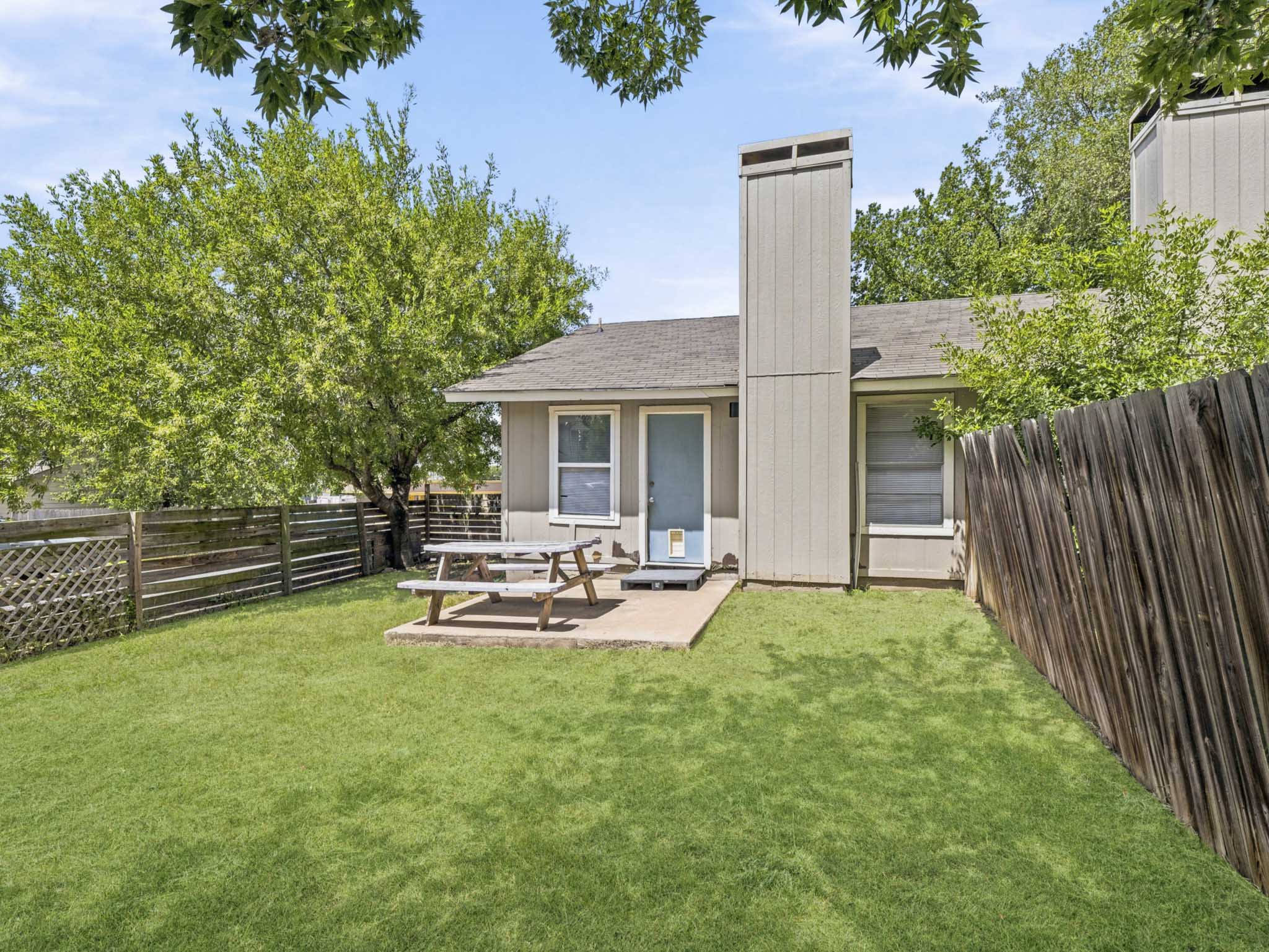 2401 Burleson Road Austin, TX 78741 - Photo 21 of 25 A fenced backyard offers a serene retreat with a compact patio perfect for outdoor enjoyment.