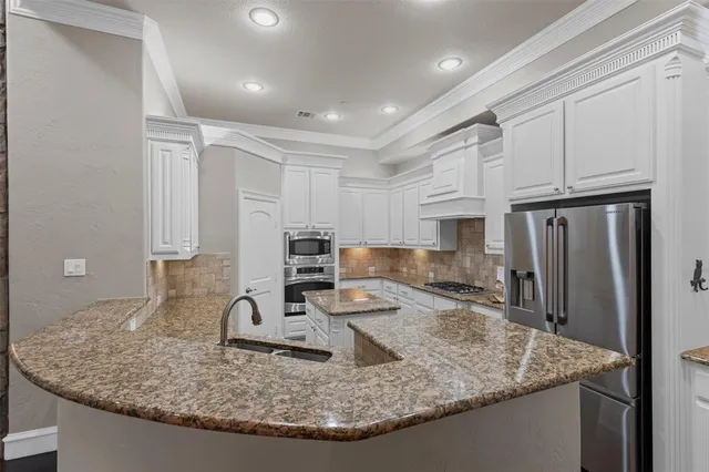 a kitchen with kitchen island granite countertop a sink a stove and a refrigerator