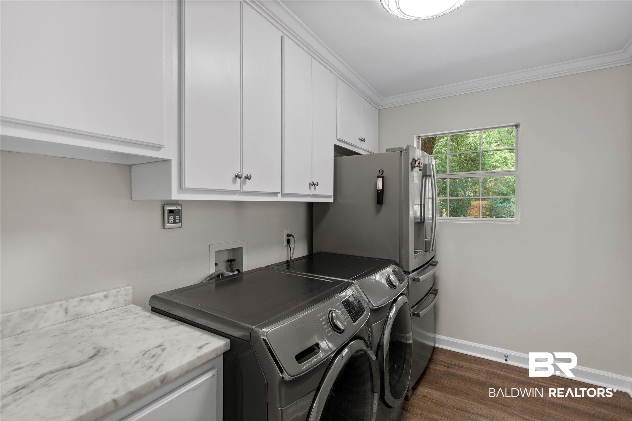 3715 Latigo Road Mobile, AL 36695 - Photo 18 of 39 Laundry room with cabinet space, washing machine and dryer, crown molding, baseboards, and dark wood-style flooring