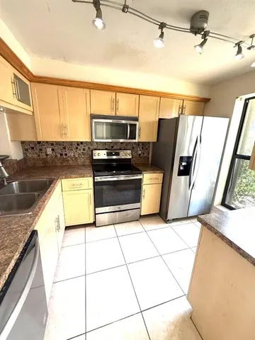 a kitchen with stainless steel appliances a sink a stove top oven a counter space and cabinets