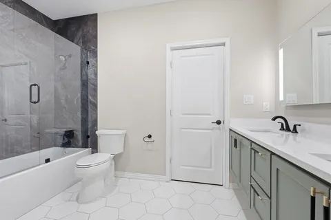 a bathroom with a granite countertop sink a toilet and shower
