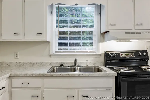 a kitchen with granite countertop a sink stove and cabinets