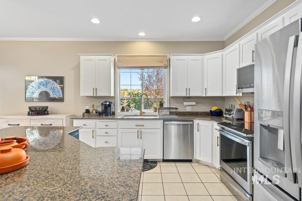 865 Fairview Drive Moscow, ID 83843 - Photo 21 of 50 Kitchen featuring stainless steel appliances, light tile patterned floors, crown molding, white cabinets, and dark stone counters