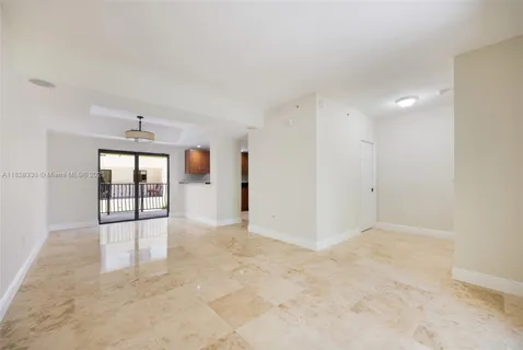 a view of an empty room with a window and kitchen view