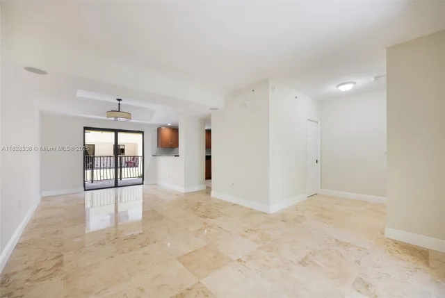 a view of an empty room with a window and kitchen view