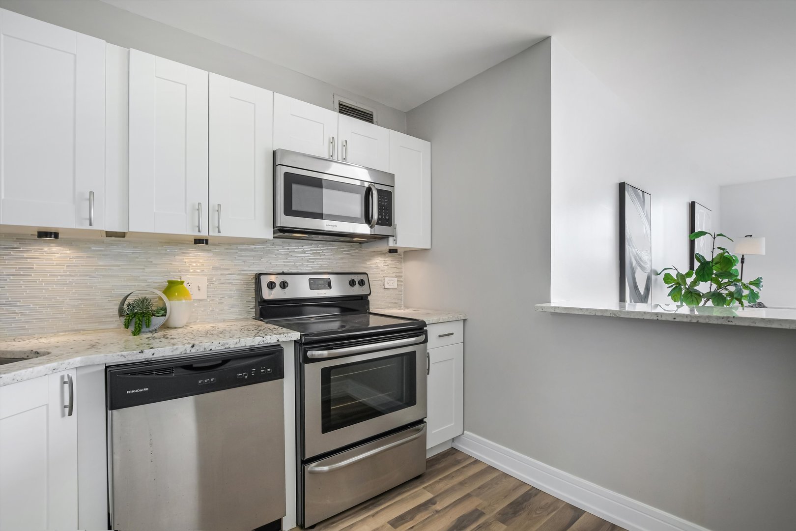 3930 North Pine Grove Avenue, Unit 2308 Chicago, IL 60613 - Photo 10 of 29 a kitchen with stainless steel appliances white cabinets and a stove top oven
