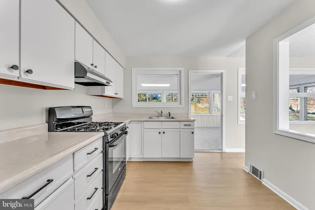 a kitchen with granite countertop white cabinets and stainless steel appliances