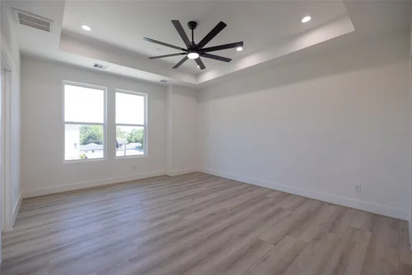 an empty room with wooden floor fan and windows