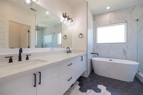 a spacious bathroom with a double vanity sink mirror and bathtub