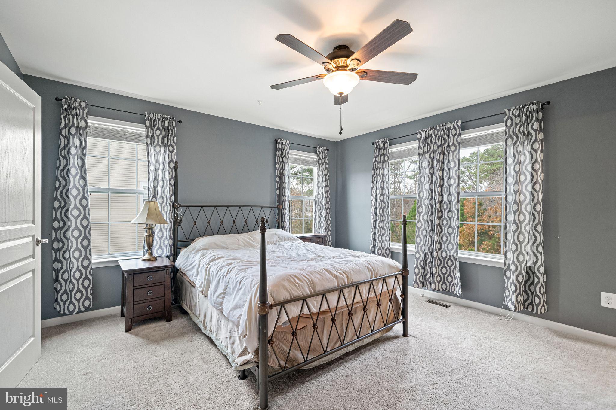 a bedroom with a large bed and a chandelier fan