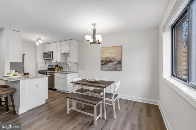 a kitchen with a dining table chairs wooden floor and appliances