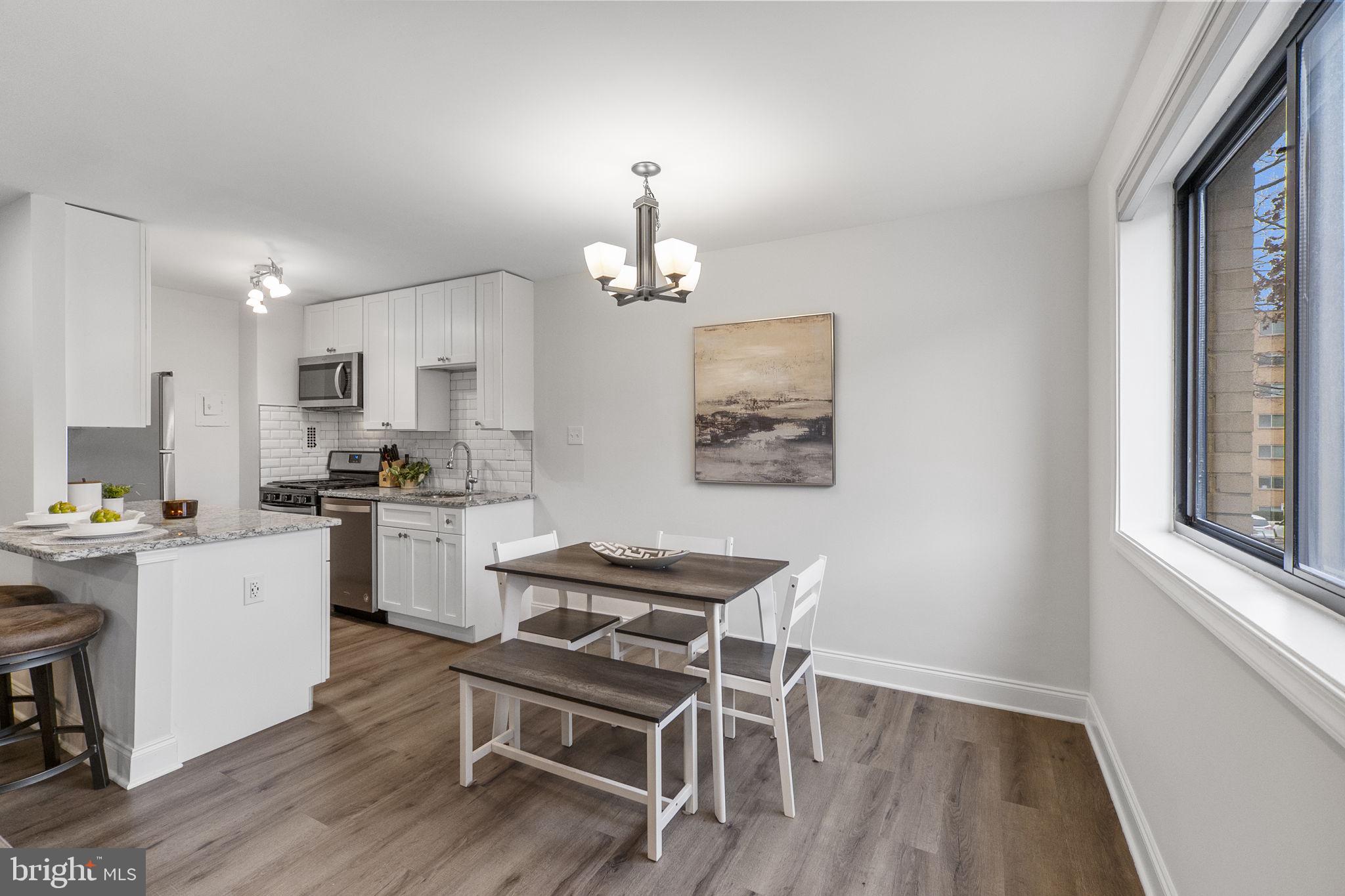 8601 Manchester Road, Unit 220 Silver Spring, MD 20901 - Photo 11 of 27 a kitchen with a dining table chairs wooden floor and appliances
