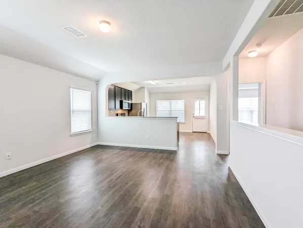 a view of a big room with wooden floor and windows