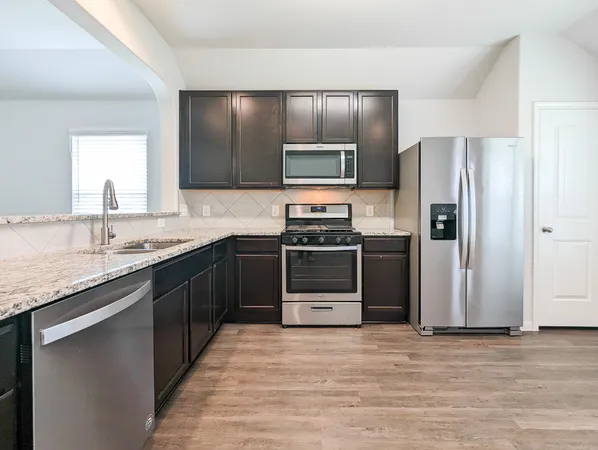 a kitchen with stainless steel appliances granite countertop a refrigerator and a stove