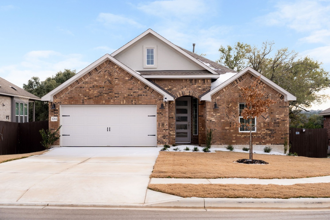 View of front facade with brick siding, driveway, and a garage