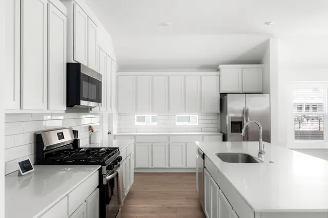 a kitchen with stainless steel appliances a stove sink microwave and cabinets