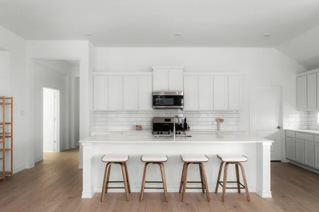 a kitchen with stainless steel appliances granite countertop a table chairs microwave and sink