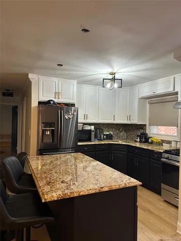 a kitchen with kitchen island granite countertop a refrigerator stove microwave and sink