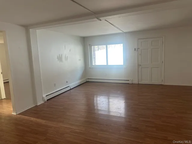 an empty room with wooden floor and windows with curtains