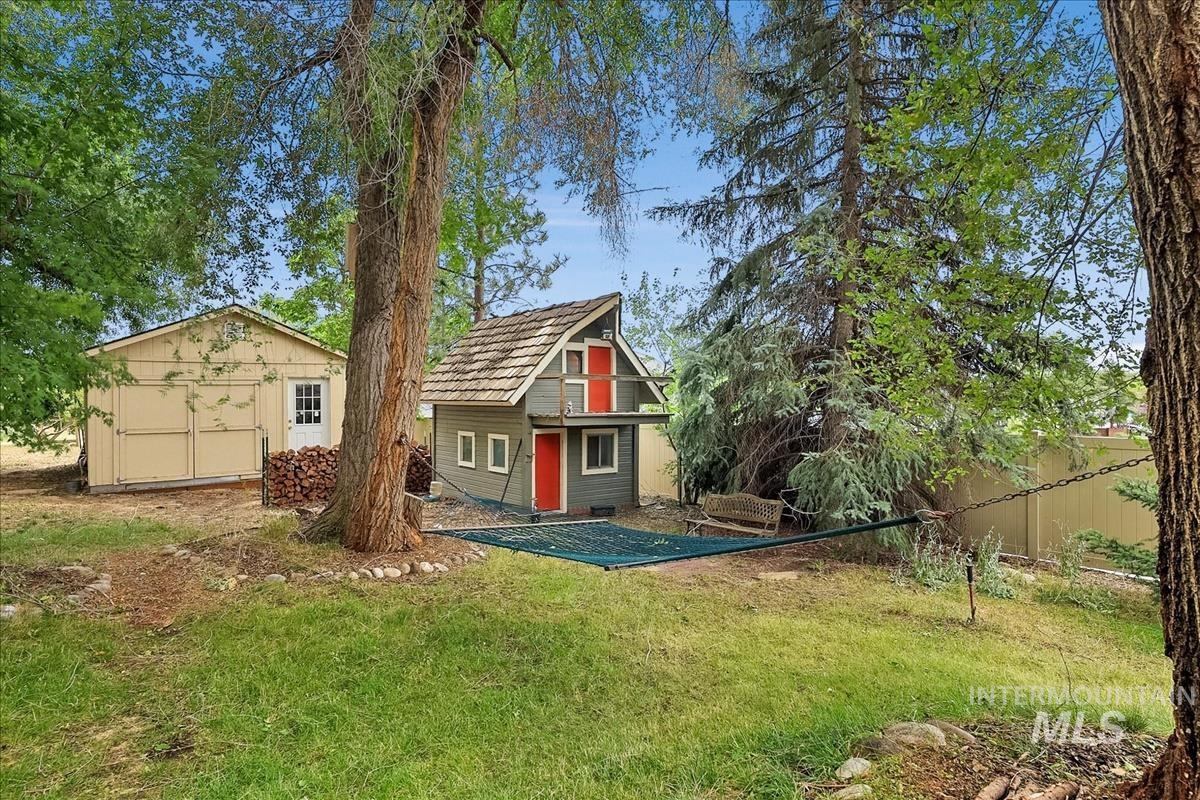 7141 West Hill Road Boise, ID 83714 - Photo 26 of 28 Expansive grass yard with mature trees and a detached outbuilding featuring a shingle roof