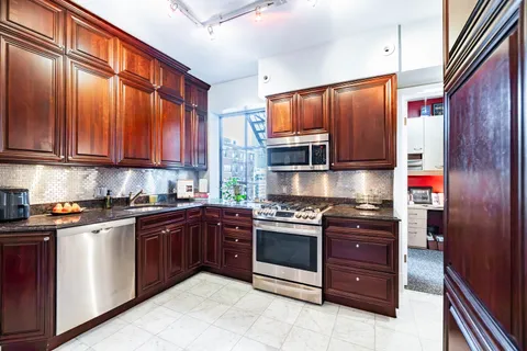a kitchen with stainless steel appliances granite countertop wooden cabinets a stove top oven a sink and dishwasher