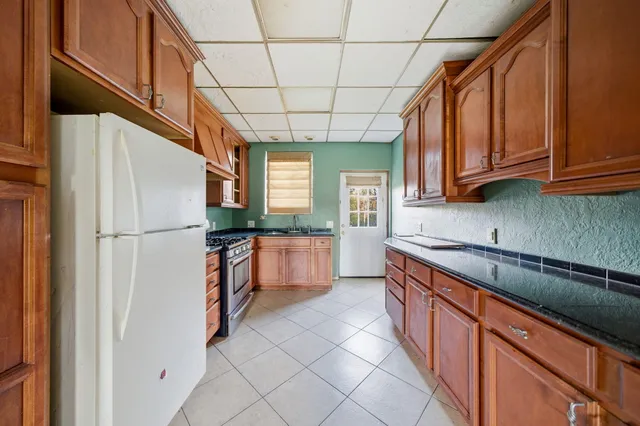 a kitchen with stainless steel appliances granite countertop a refrigerator a sink dishwasher a stove and white countertops with wooden floor