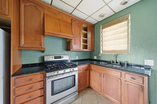 a kitchen with granite countertop stainless steel appliances a sink stove and cabinets