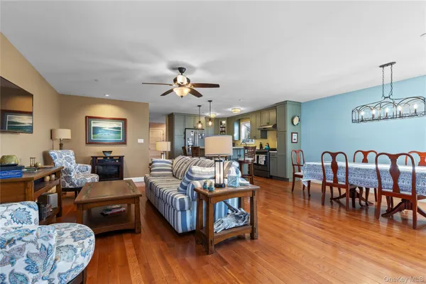 a living room with furniture kitchen view and a wooden floor