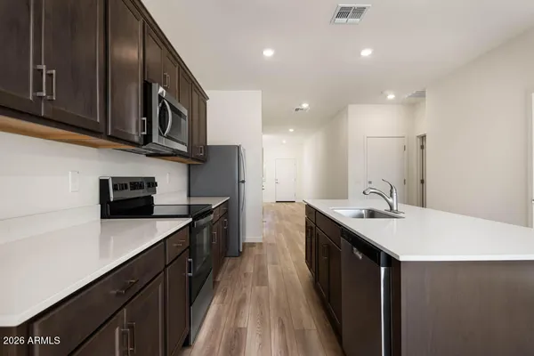 a kitchen with stainless steel appliances granite countertop a sink a stove top oven a refrigerator with wooden cabinets and floor